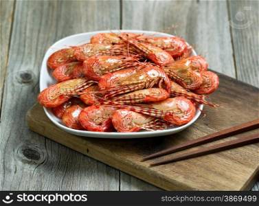 Close up image of cooked shrimp in white plate on top of server with rustic wood underneath.