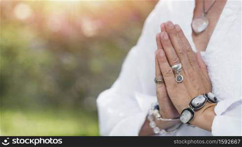 Close up image of female hands in prayer position outdoor. Self-care practice for wellbeing. Self-Healing Meditation. Hands in a Prayer Position