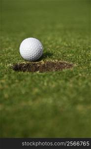 Close up image of golf ball close to the hole.