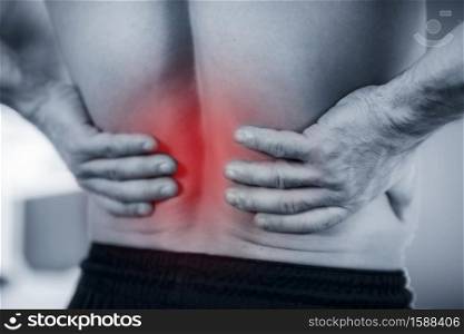 Close up image of male holding painful lower back.