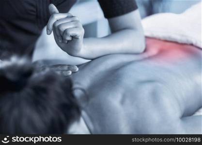 Close up image of physiotherapist massaging female patient with injured lower back muscle. Blue colored image. Red accent on the back. Sports injury treatment.