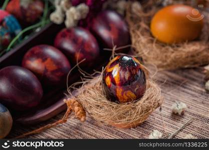 Close up image of shiny colorful Easter egg in nest. Eggs painted with onion skins. Easter holiday concept.