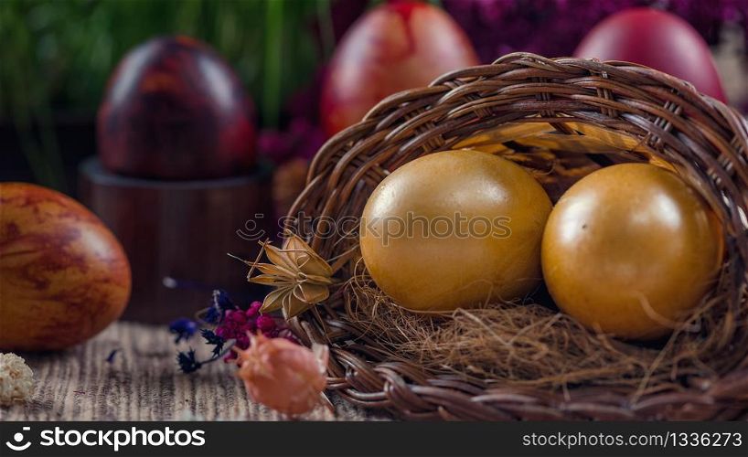 Close up image of two beautiful golden Easter eggs in wicker basket. Green grain grass decoration in background. Easter holiday concept.