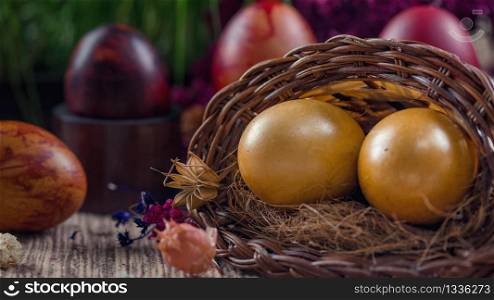 Close up image of two beautiful golden Easter eggs in wicker basket. Green grain grass decoration in background. Easter holiday concept.