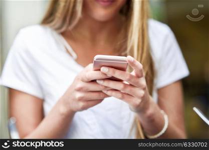Close-up image of young blonde girl texting with smartphone, female hands typing text message via cellphone, social networking concept