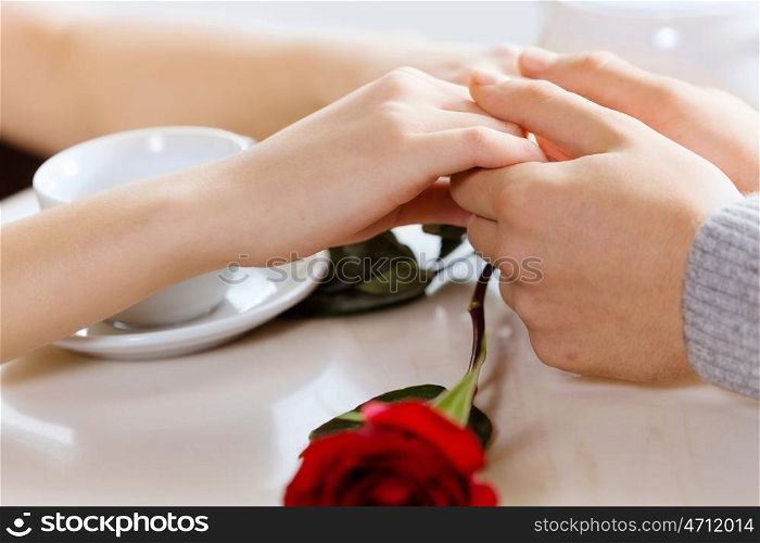 Close up image of young couple holding hands having date at cafe