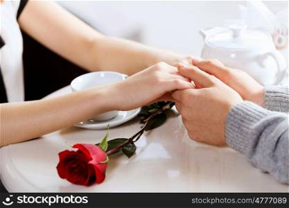 Close up image of young couple holding hands having date at cafe