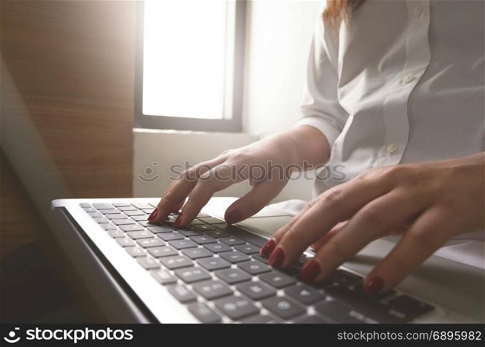 Close-up image of young woman hands typing and writing massages on laptop,working on cafe or home.