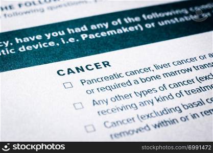 Close up image, selective focus on cancer disease content on health insurance questionnaire and application form. Healthcare, insurance policy, personal safety plan, business concepts.
