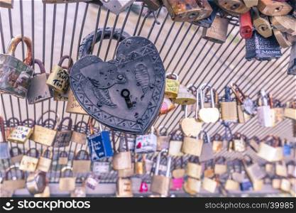 Close up image with an old metallic heart shaped lock, caught on a fence. Suitable for a love concept or background.