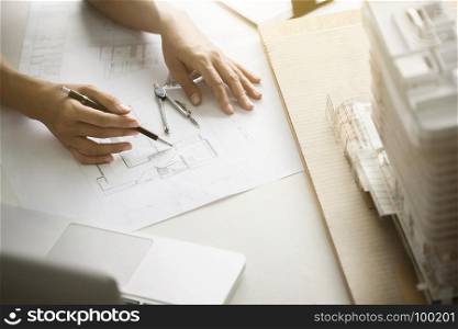 close up interior Architect working on blueprint with engineering tools