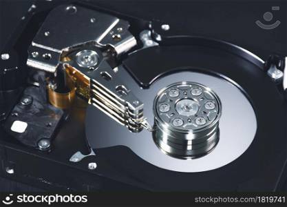 Close up internal of hard disk drive having a metal alloy disc platters and actuator arms inside with component