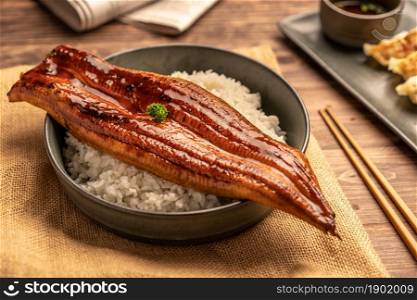 Close-up Japanese grilled eel served over rice or Unagi don set on plate. Japanese food on restaurant table