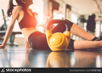 Close up kettlebells with woman exercise workout in gym fitness breaking relax after sport training center background. Healthy lifestyle bodybuilding and athlete muscle dumbbells. Healthcare lifestyle