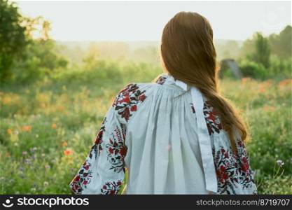 Close up lady in traditional dress concept photo. Beautiful field. Back view photography with sunlit meadow on background. High quality picture for wallpaper, travel blog, magazine, article. Close up lady in traditional dress concept photo