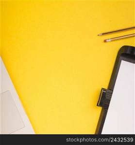 close up laptop pencils printer tray with blank paper yellow background