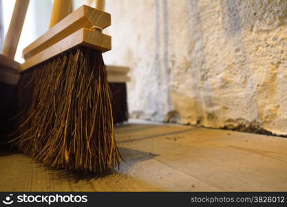 Close up large brooms for house work on old wooden floor of country house. Sweeping