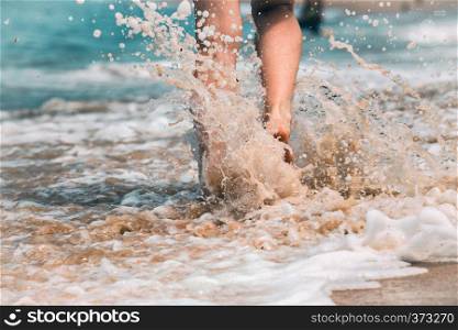 close up leg of young woman walking along wave of sea water and sand on the summer beach. Travel Concept.