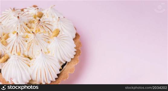 close up lemon tart with italian meringue pink backdrop