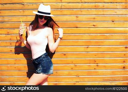 Close up lifestyle fashion portrait of woman posing on the street drinking smoothie, wearing stylish outfit and sunglasses, summer hat, joy, relax, vacation.
