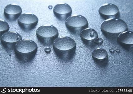 Close up macro of sparkling blue water drops on textured surface with copy space.