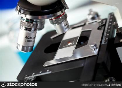 Close up macro photograph of microscope with slide in a scientific research laboratory.