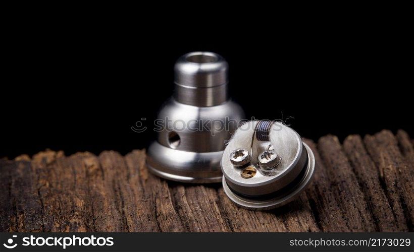 close up, macro shot of high end rebuildable dripping atomizer for flavour chaser on natural wood texture background, vaping device, selective focus