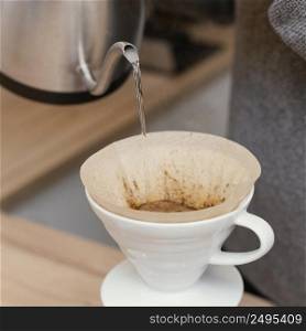 close up male barista pouring hot water coffee filter
