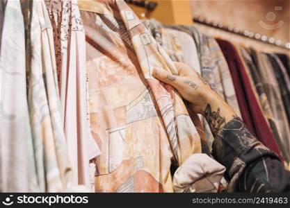 close up male customer s hand choosing shirt hanging rail shop