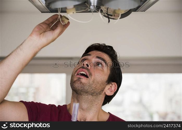 close up male electrician installing holder ceiling light
