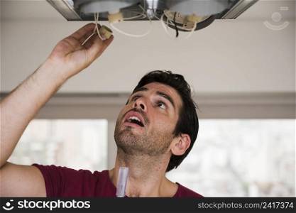 close up male electrician installing holder ceiling light