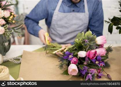 close up male florist cutting paper wrapping flower bouquet. Beautiful photo. close up male florist cutting paper wrapping flower bouquet