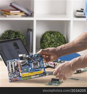 close up male technician holding modern computer motherboard from table