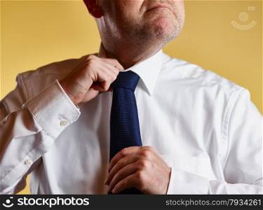 Close up, male wearing white shirt and blue tie, he loosen the tie knot, yellow background