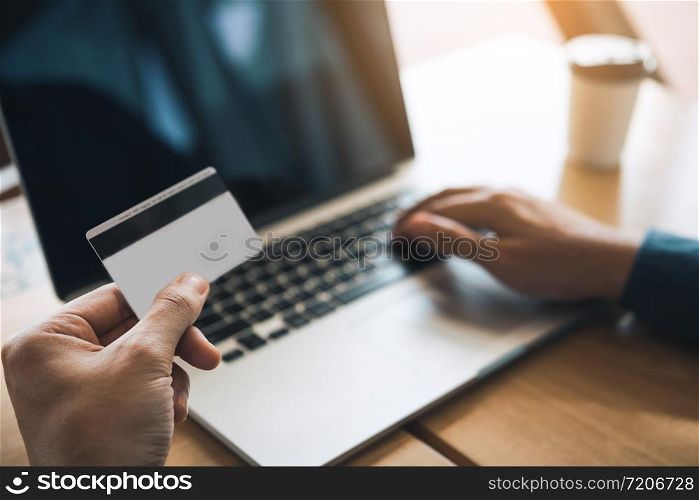 Close up man hand holding credit card and typing laptop keyboard with shopping online concept.