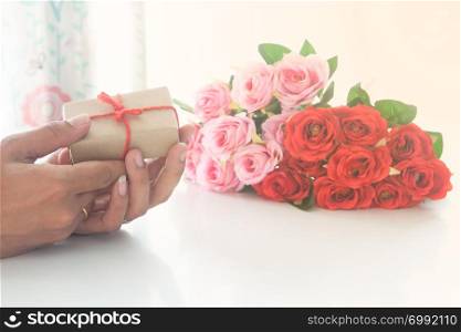 Close up man hands holding gift box and roses on white background