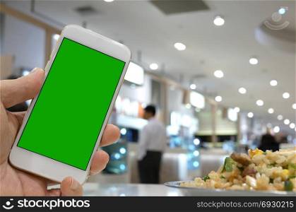 Close up man holding green screen phone with blur people eating food inside mall
