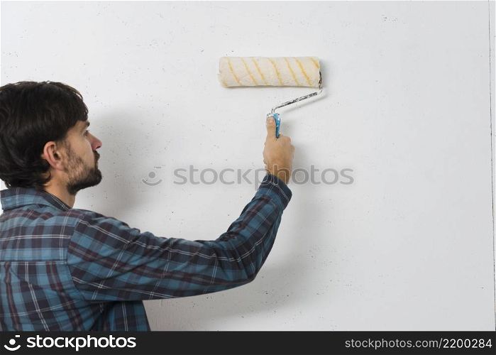 close up man painting wall with paint roller