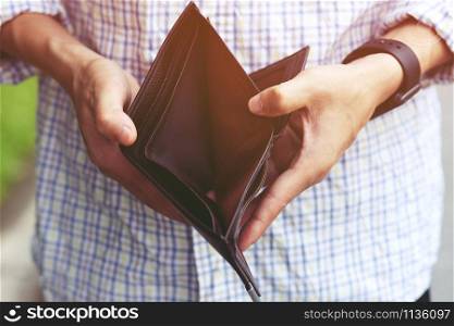 close up man person holding an empty wallet in the hands of an man no money out of pocket. finance savings concept