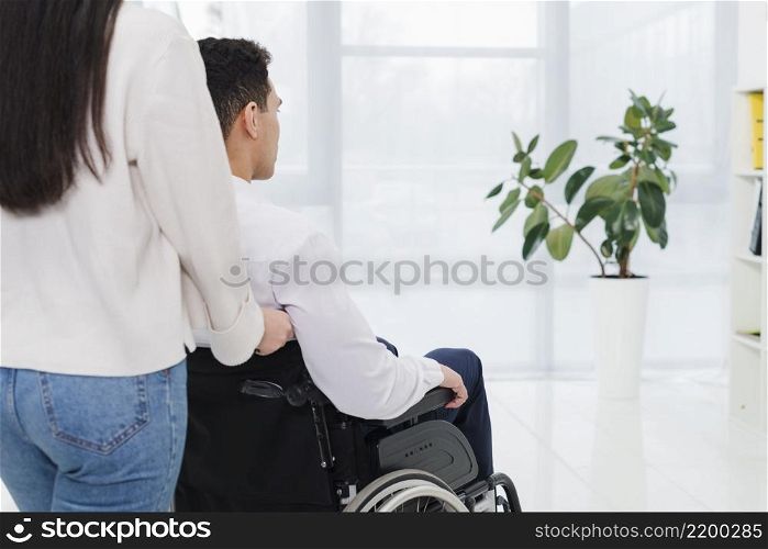 close up man pushing woman wheelchair