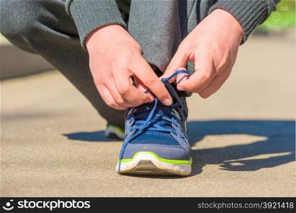 close-up man&rsquo;s hands tied shoelace on the asphalt