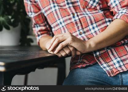 close up man s clasped hand wooden table