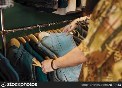 close up man s hand choosing blue jacket hanging rail clothing shop