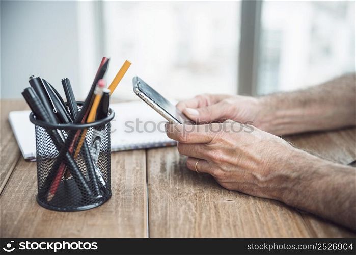 close up man s hand holding smart phone hand wooden desk