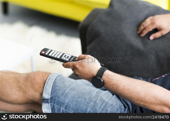 close up man s hand holding television remote control