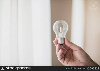 close up man s hand holding transparent light bulb