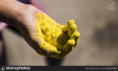 close up man s hand holding yellow holi color