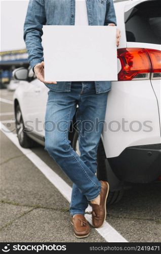 close up man standing near car road showing blank white placard