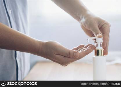 Close up man using bottle of antibacterial wash hand sanitizer gel dispenser, against Novel coronavirus (2019-nCoV) at home. Home isolation and Healthcare concept. COVID-19.