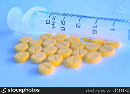 close-up medication in tablets and insulin syringe in blue tone blurred background